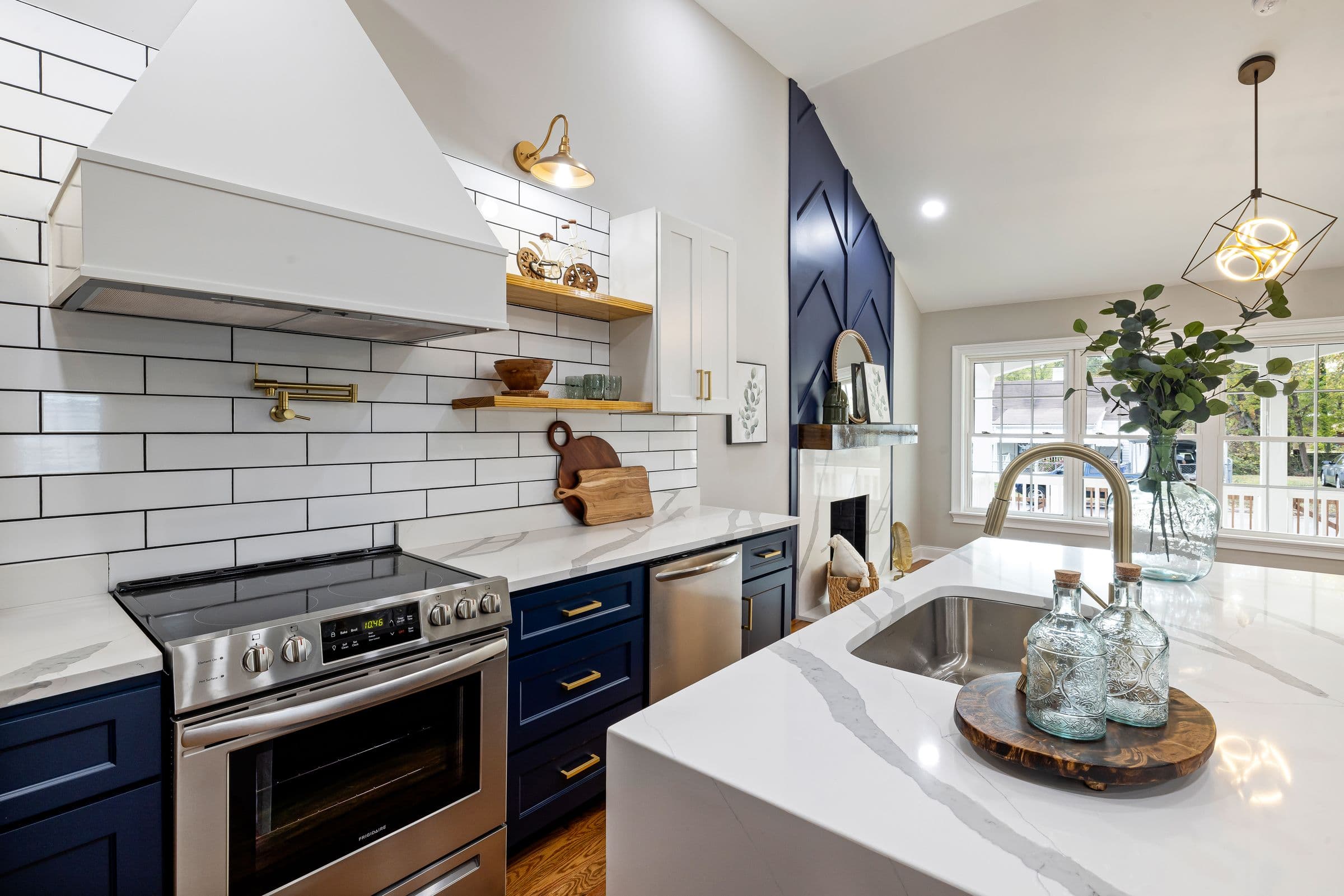 A finished kitchen with navy cabinetry, brass hardware and a stone island