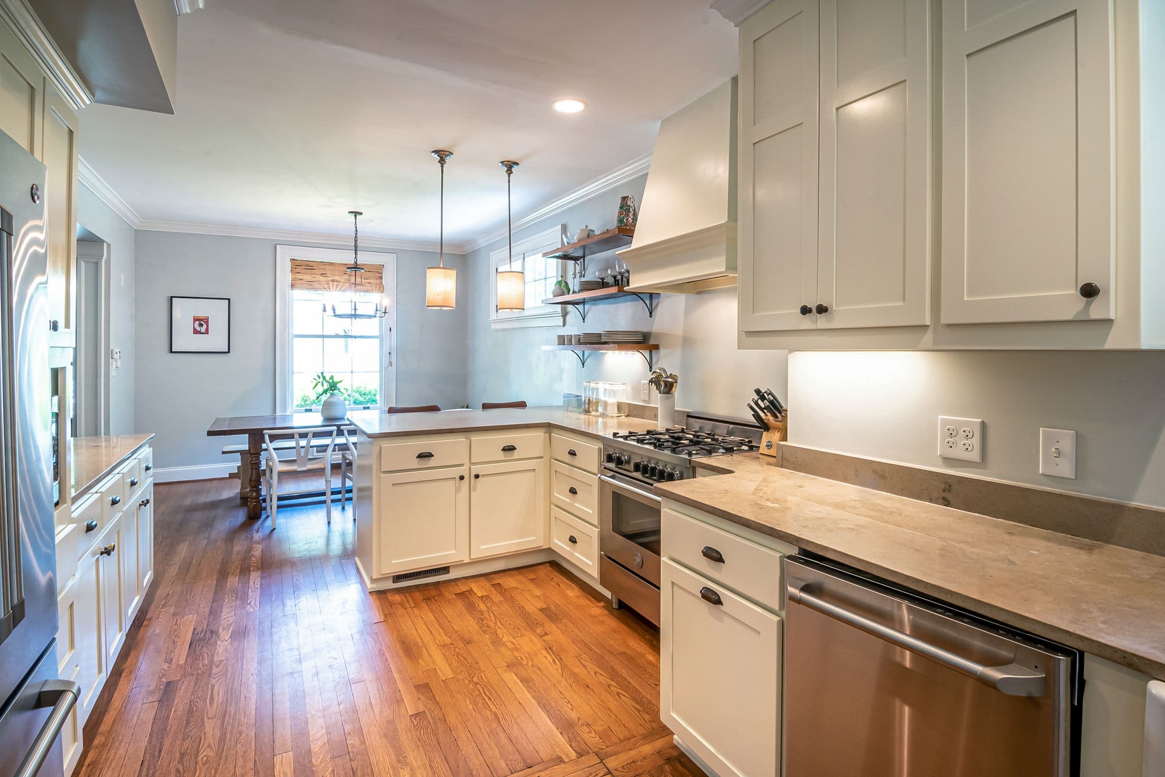 A finished kitchen with cream cabinetry, stone counters and wood flooring