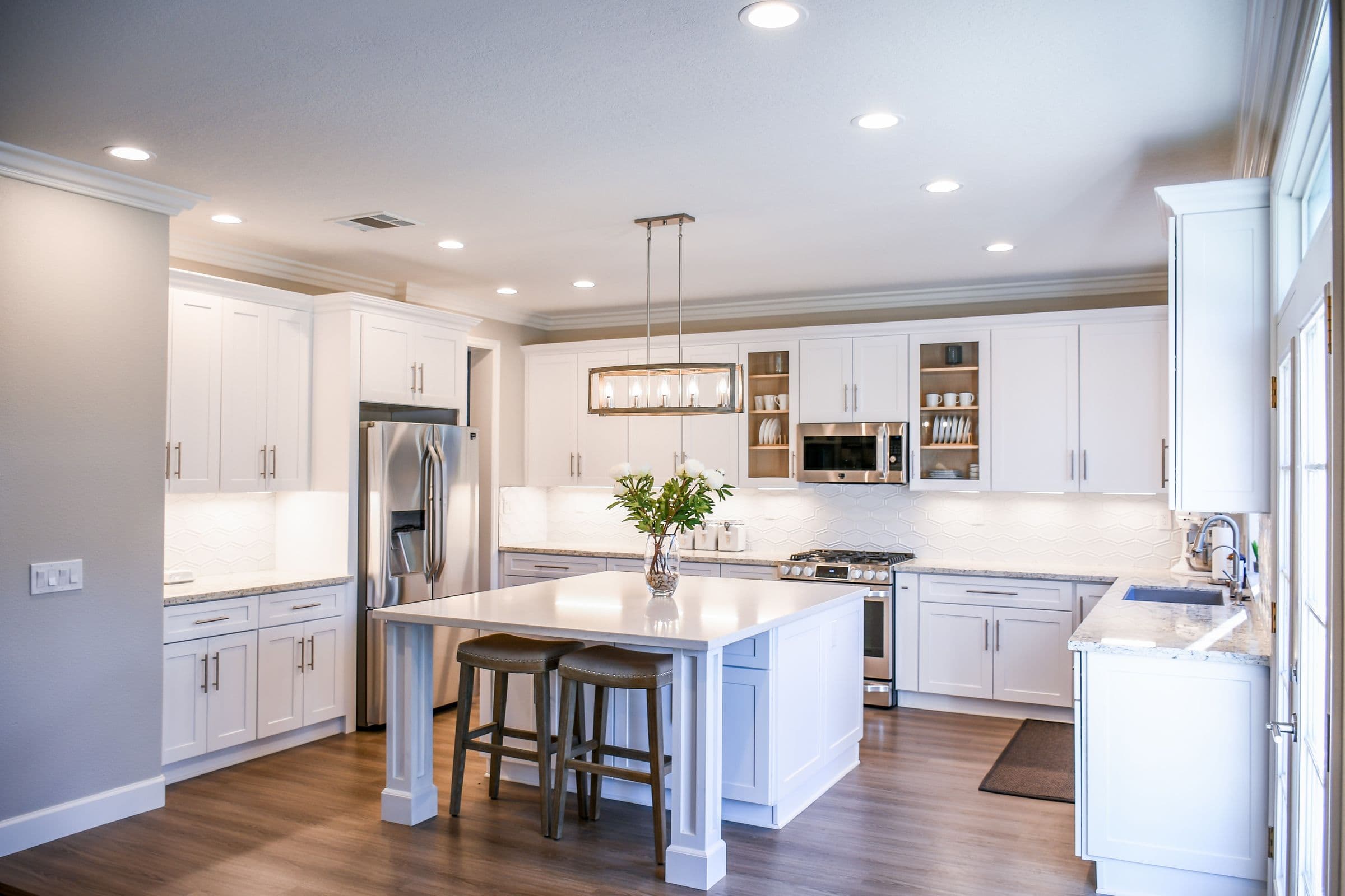 A white shaker kitchen with a central island and wood flooring